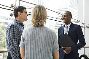 Insurance agent standing with clients in hallway