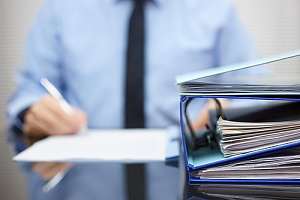 Person with binders and paperwork on desk