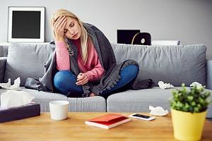 Woman with individual health insurance with a cold sitting on couch