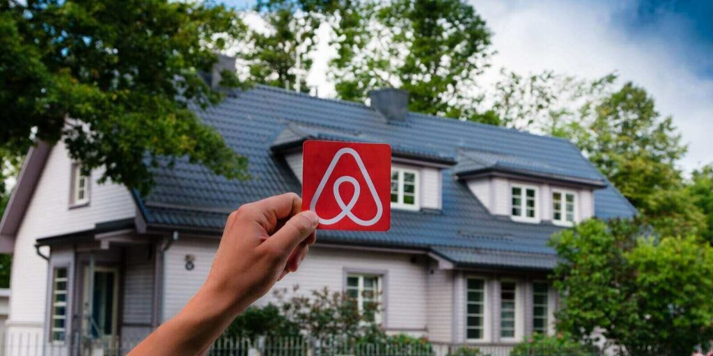 logo airbnb and the old beautiful house with green garden on the background