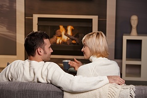 couple relaxing by a wood burning fireplace with Landlord Insurance
