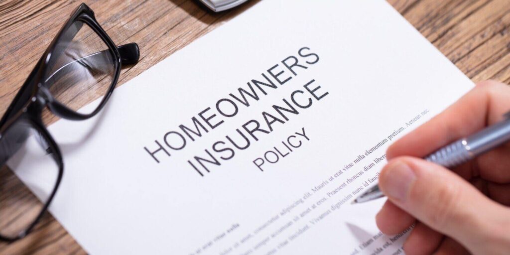 filling homeowners insurance policy form over wooden desk