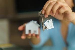 hand holding house key and house model