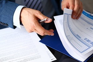 male arm in suit offer insurance Landlord Forms clipped to pad and silver pen to sign closeup