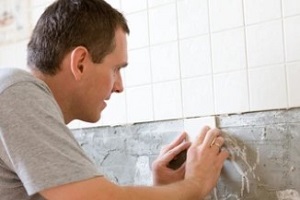 man repairing bathroom tiles