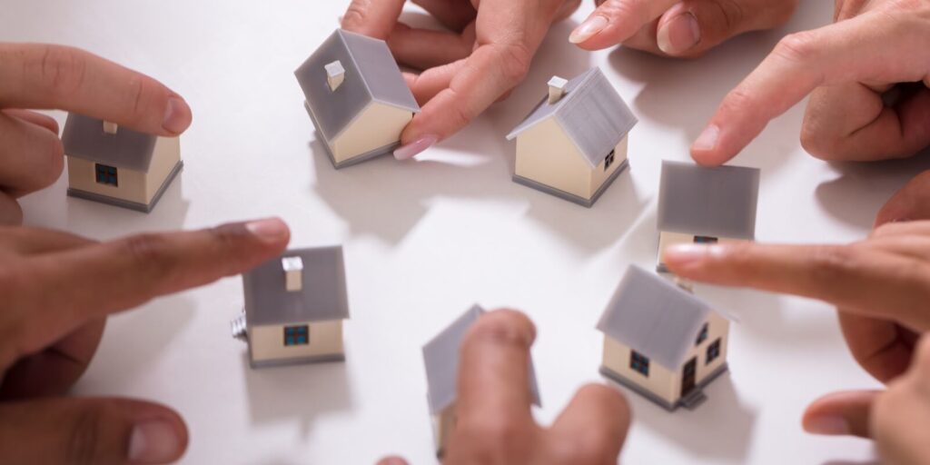 group of people touching miniature house on white background
