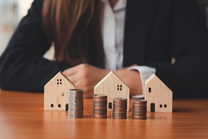 landlord with multiple wooden toy home and stack of coins