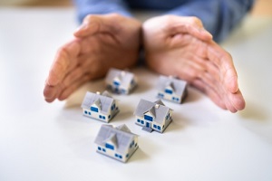 hand protecting miniature houses on the desk