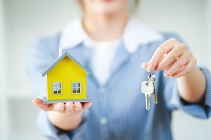 women holding a house model and house keys