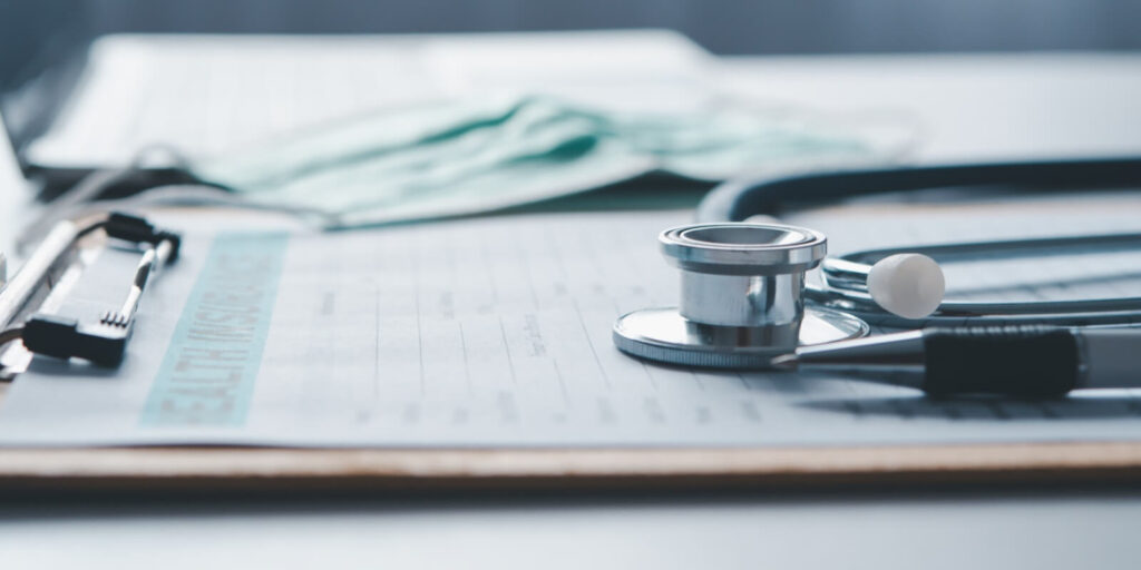 stethoscope and calculator placed on health insurance documents