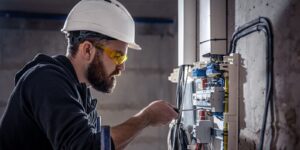 electrician works in a switchboard with an electrical connecting cable