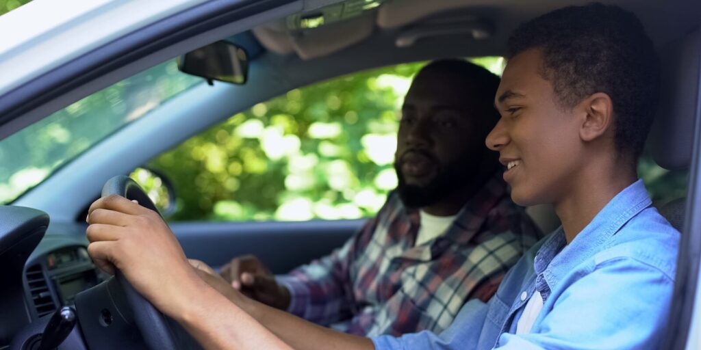 parent teaching son how to drive car, spending time together