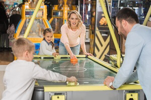 family playing air hockey together in entertainment center