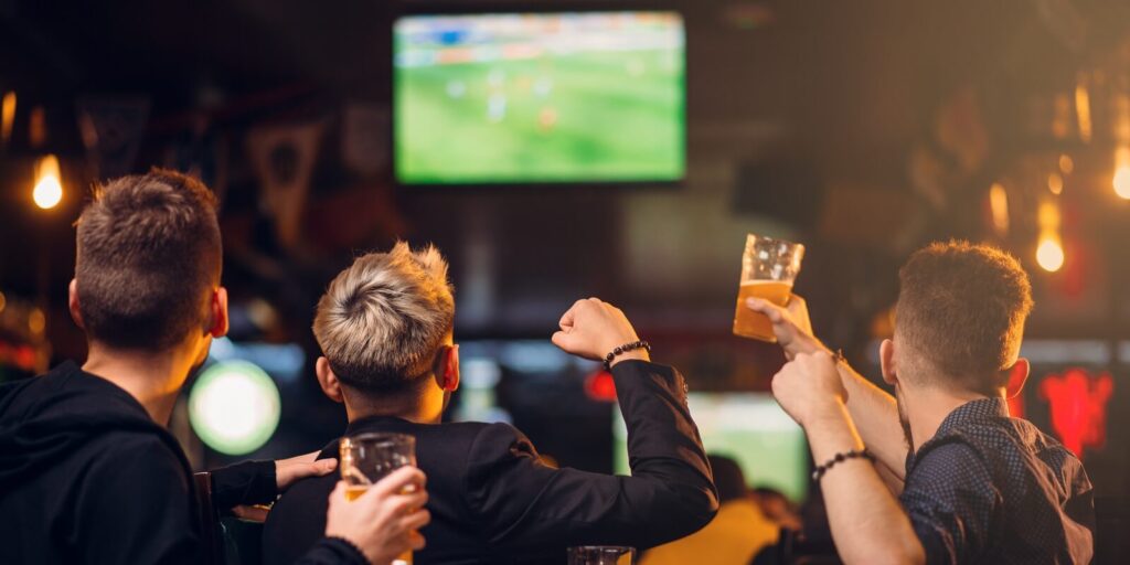 three men watches football on tv in a sport bar