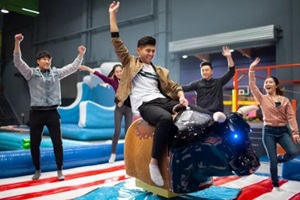 group of friends riding mechanical bull