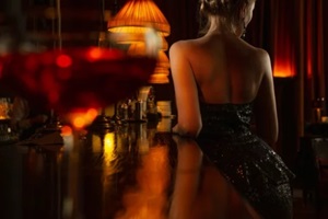 back of elegant lady in black shiny evening dress staing near bar counter