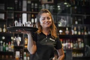 waitress carries a whiskey glass on a tray in hotel restaurant, bar