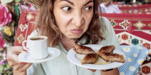 woman sniffs dessert in a cafe with disgust on her face