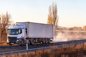 truck with a shipping container driving on a highway