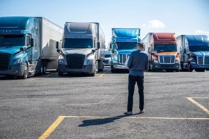 truck driver carries a shopping box in his hands and going to his big rig semi ruck parked on the truck stop parking lot