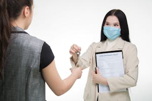 Woman Handing Over Key to Tenant with Holding Home Insurance Policy Form