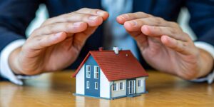 Hands Protecting Model Home Representing Homeowners Insurance