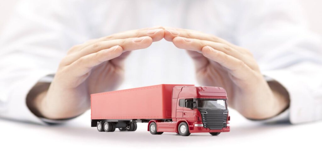 Hands Covering Red Commercial Truck Representing Trucking Insurance