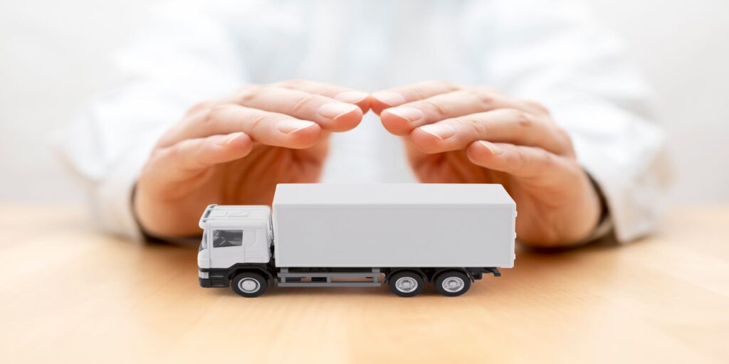 White Truck Protected by Hands Representing Trucking Insurance Concept