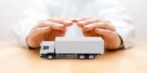 White Truck Protected by Hands Representing Trucking Insurance Concept