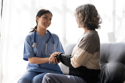 Elderly woman talking to a staff member in scrubs inside an assisted living facility