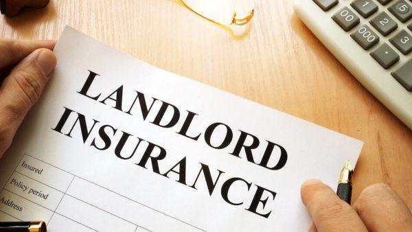 Landlord insurance document held on a desk.