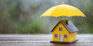 Miniature House Under Yellow Umbrella Showing Home Hnsurance